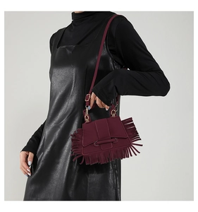 Détail d'un sac bandoulière bordeaux avec de longues franges et détails dorés