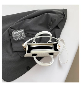 Top view of white croc-embossed handbag showing internal zipper compartment and strap