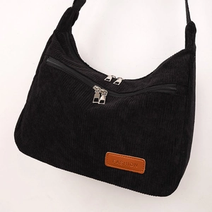 Detail of black corduroy fabric texture and silver zippers on women's shoulder bag
