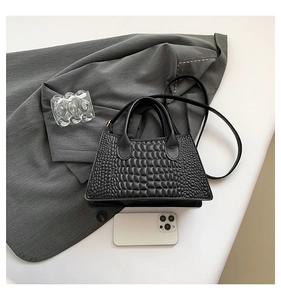 Detail of black crocodile-embossed PU leather texture on a stylish trapezoid handbag