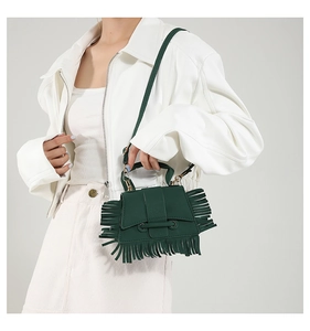 Détail d'un sac bandoulière vert foncé avec de longues franges et détails dorés