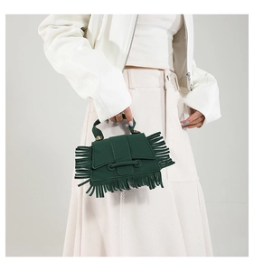 Détail d'un sac à main vert foncé à franges en similicuir mat et ferrures dorées