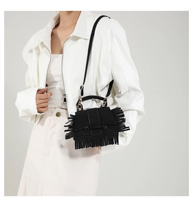 Détail du sac bandoulière noir avec des accents de franges denses et une sangle en cuir