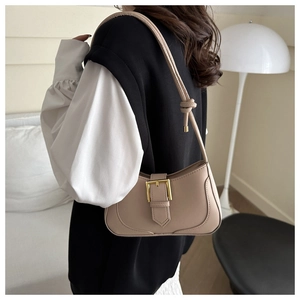Détail du sac hobo beige avec grande boucle dorée et design de bandoulière à nœuds