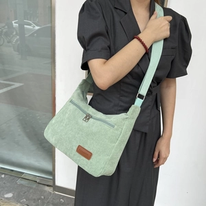 Women's mint green corduroy crossbody bag with a fashion label and zip front pocket