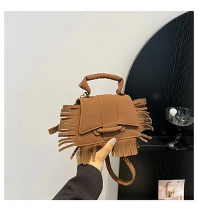 Détail du sac à main en similicuir marron montrant des franges et une boucle ronde