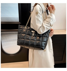 Detail of black quilted puffer tote bag with gold chain strap and elk charm pendant