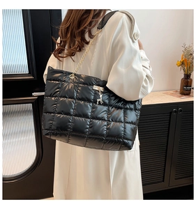 Detail of black quilted puffer tote bag with gold reindeer charm and chain strap