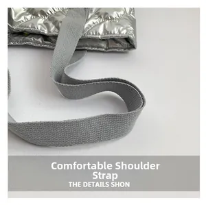 Detail view of the metallic silver quilted fabric and wide grey woven shoulder strap