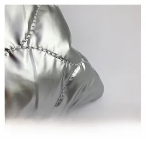 Detail of silver metallic quilted fabric showing large diamond pattern and glossy finish