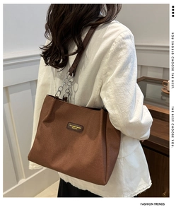 Close-up of brown canvas tote bag with silver chain strap and fashion brand label