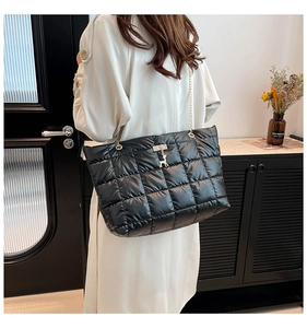 Detailed view of black quilted tote bag with gold chain strap and deer charm on a model