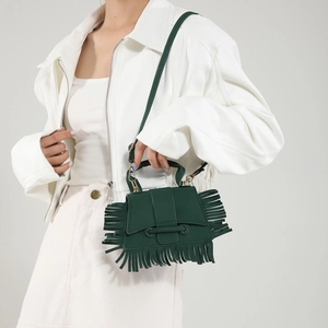 Sac bandoulière vert foncé à franges avec sangle réglable porté par un mannequin femme