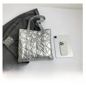 Silver quilted tote bag shown with a tablet and phone for scale reference on white table