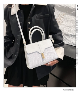 Gros plan du sac blanc à texture crocodile porté par un mannequin en tailleur noir