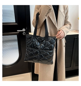 Close-up of black quilted puffer tote bag with diamond stitching texture