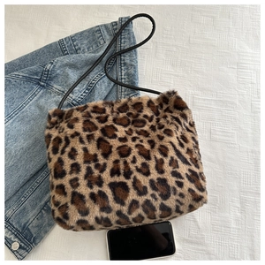 Vista plana del gran bolso tote de felpa con estampado de leopardo en sábanas blancas