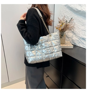 Detail of silver quilted tote bag with metallic finish and gold chain shoulder strap