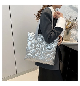 Detail of silver quilted tote bag with metallic finish and wide gray textile strap