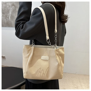 Model showing beige canvas tote bag with leather chain strap and minimalist text