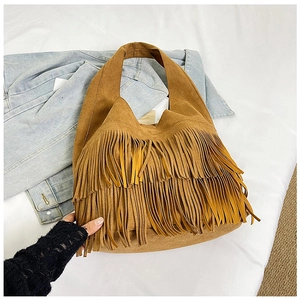 Detailopname van de bruine suède schoudertas met franjes op een casual denim achtergrond