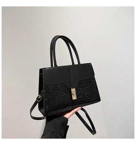 Close-up of black stone textured leather tote with elegant gold metal twist lock buckle