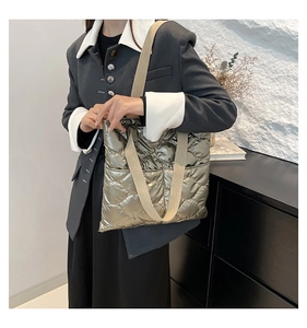 Close-up of a quilted metallic gold tote bag with wide beige fabric shoulder strap