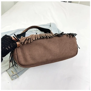 Detail view of coffee suede bucket bag with long fringe tassels on denim background