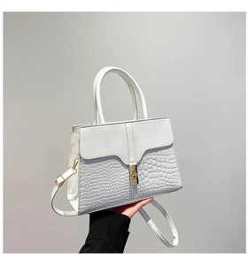 Detail of white faux leather tote with crocodile pattern embossing and gold metal lock
