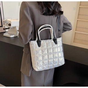 Close-up of white quilted puffer tote bag with black straps and shiny waterproof fabric