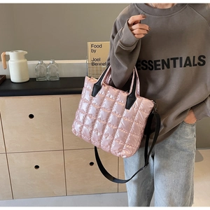 Pink quilted crossbody bag with glossy metallic finish and black adjustable strap