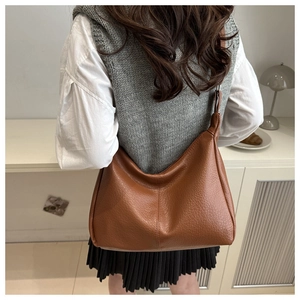 Brown lychee-texture leather shoulder bag shown on model in a modern indoor setting