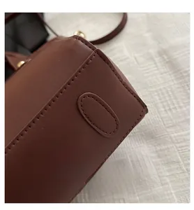 Detail view of dark brown leather bucket bag showing fine stitching and gold hardware