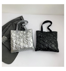 Close-up of quilted puffer tote bags in silver and black with wave stitch texture