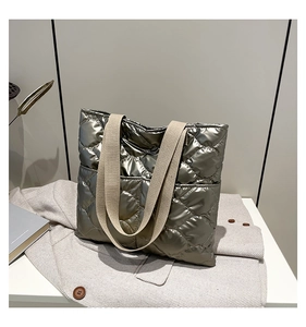 Macro view of metallic quilted tote bag texture with large diamond stitching and front pocket