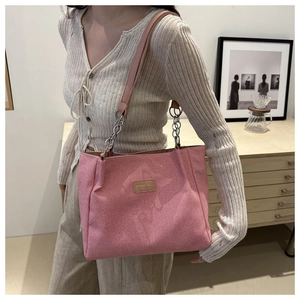 Detailed view of pink fabric tote bag featuring leather logo patch and silver chain strap
