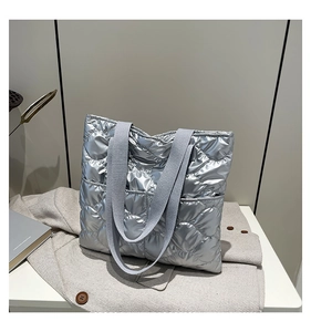 Detail of silver metallic quilted tote bag featuring a large capacity and wide straps
