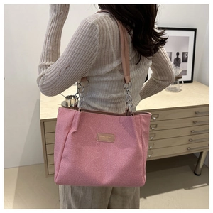 Pink fabric tote bag with elegant chain strap shown on model in a modern home setting