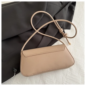 Detailed view of beige shoulder bag with decorative knot strap on minimal background