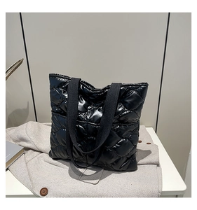 Detail of black quilted tote bag with glossy finish and rhombus pattern textures