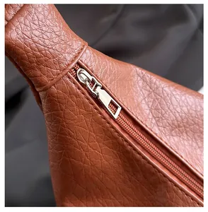Close-up of smooth silver zipper and lychee grain leather texture on terracotta bag