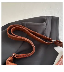 Detail of brown litchi pattern leather strap with silver metal buckle on a tote bag