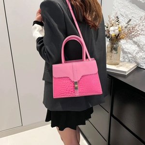 Rose pink handbag with crocodile texture and gold clasp shown from a side view on model
