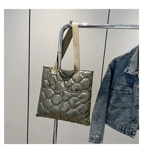 Close-up of golden quilted tote bag with metallic finish and off-white woven straps