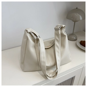 Detail of off-white tote bag with lychee texture and silver zippers on minimalist table