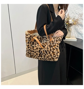 Detail of leopard print plush tote bag with brown faux leather handles worn by model