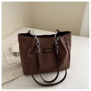Detail of dark brown tote bag showing woven texture and silver chain leather strap