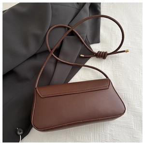 Close-up of brown matte leather shoulder bag with circular lock and knotted rope strap