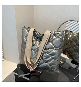 Detailed macro view of metallic silver quilted tote with wide beige textile strap