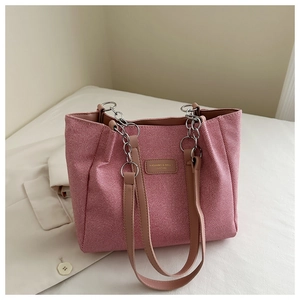 Detailed close-up of pink fabric tote bag with leather tag and chain strap handles